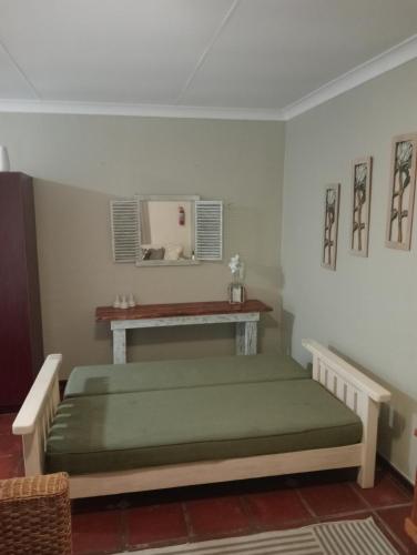 a bed in a room with a table and a mirror at A Cherry Lane Self Catering and B&B in Bloemfontein
