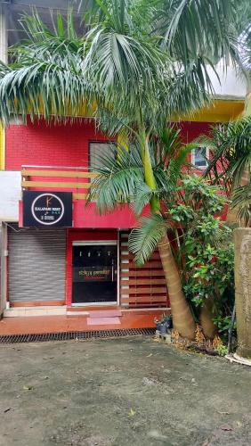 a red building with a palm tree in front of it at Kalapani Hostel in Port Blair