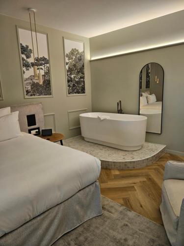 a bedroom with a tub and a bed and a mirror at L'Orée du Bois - Hôtel & Spa in Montagudet