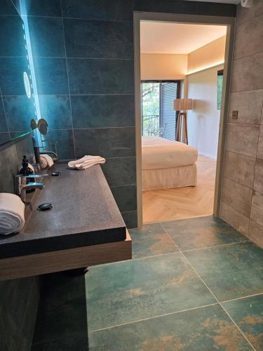 a bathroom with a sink and a bed in a room at L'Orée du Bois - Hôtel & Spa in Montagudet