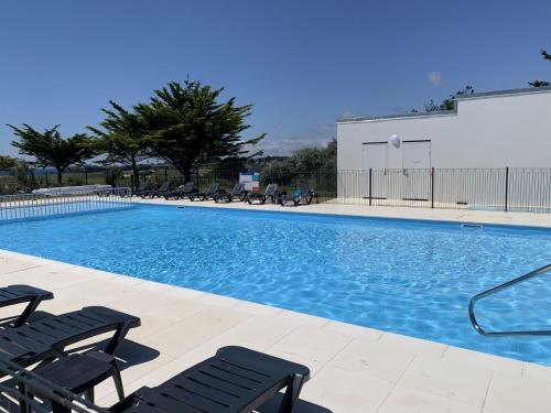 une grande piscine avec des chaises et un bâtiment dans l'établissement Studio duplex face à la mer, à Guidel