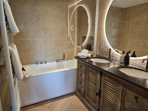 a bathroom with two sinks and a tub and a mirror at L'Orée du Bois - Hôtel & Spa in Montagudet
