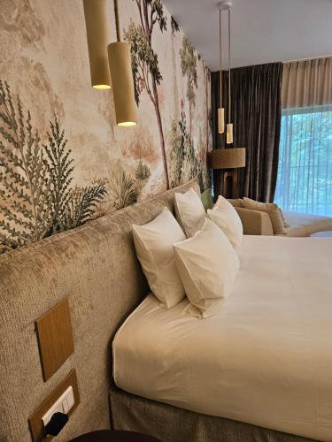 a bedroom with a bed and a couch with pillows at L'Orée du Bois - Hôtel & Spa in Montagudet