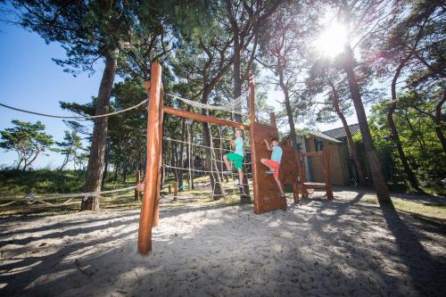 two people playing on a swing set in a park at Aquamaris Strandresidenz Rügen in Juliusruh