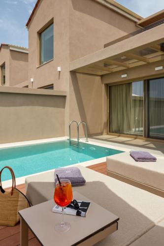 a drink on a table next to a swimming pool at Scarabeo Suites & Villas Parga in Parga