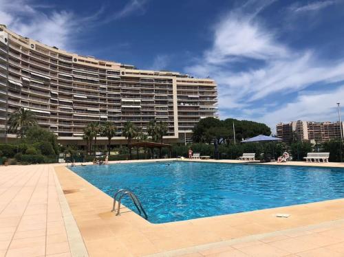 une piscine avec un grand bâtiment en arrière-plan dans l'établissement Luxury Apartment 4 w Pool, Sea and Mountain Views, à Mandelieu-la-Napoule
