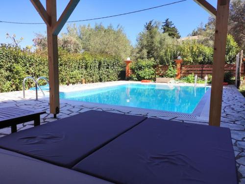 a blue swimming pool with a pergola next to it at Villa Loula google it in Lygia