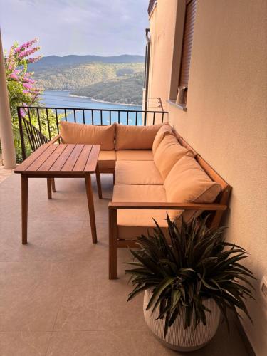a couch and a table on a balcony with a view at Amor, flat with private hot tub, breathtaking views and free parking in a garage, bookable all year round, Also take a look at our flat Coccolina in Rabac