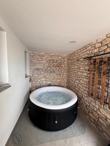 a round bath tub in a room with a brick wall at Amor, flat with private hot tub, breathtaking views and free parking in a garage, bookable all year round, Also take a look at our flat Coccolina in Rabac