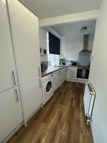 a kitchen with white cabinets and a washer and dryer at Old Town View in Jedburgh