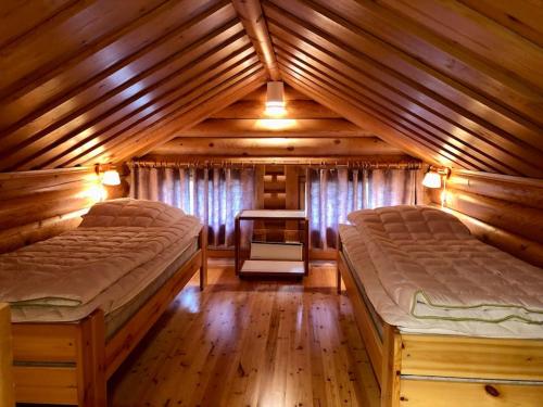 a bedroom with two beds in a wooden cabin at Villa Rukan Honka in Ruka