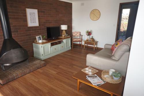 a living room with a couch and a fireplace at Cakebread Cottage in Encounter Bay