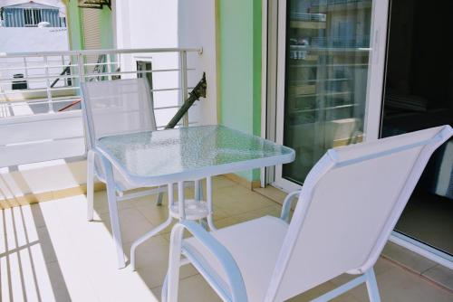 a glass table and two white chairs on a balcony at B3 Irene in Thérissos