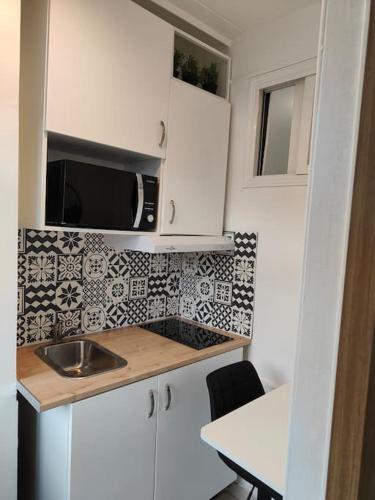 une petite cuisine avec un évier et un micro-ondes dans l'établissement 2 pièces lumineux à 5 min à pied Stade de France, à Saint-Denis