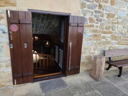 a wooden door in a stone building with a bench at Harritarte Getaria in Getaria
