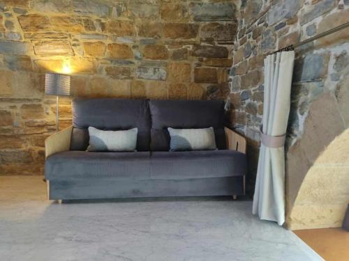 a blue couch in a room with a stone wall at Harritarte Getaria in Getaria