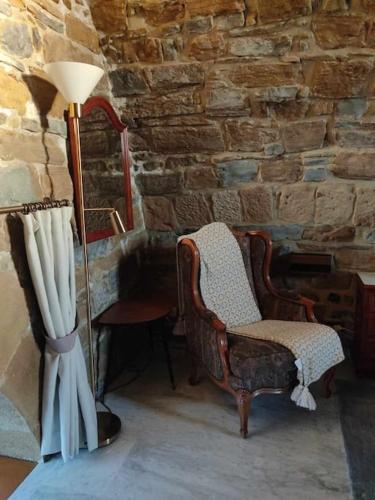 a room with two chairs and a lamp and a stone wall at Harritarte Getaria in Getaria