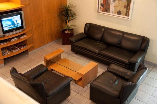 een woonkamer met een leren bank en een salontafel bij Hotel Linhatur in Linhares