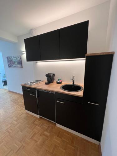 a kitchen with a sink and black cabinets at rs44 Apartments über den Dächern von Bregenz in Bregenz
