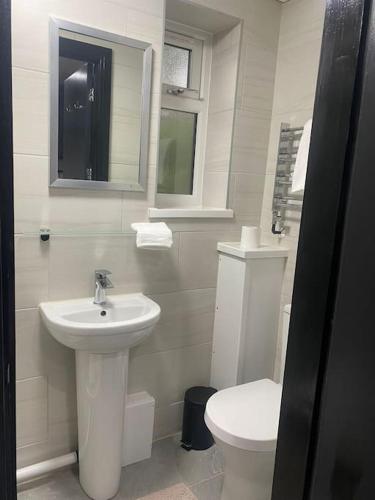 a white bathroom with a sink and a toilet at The Courtyard - By Casa Living in Canley