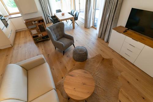 a living room with a couch and a table and a television at Waldrand Apartments in Ramsau am Dachstein