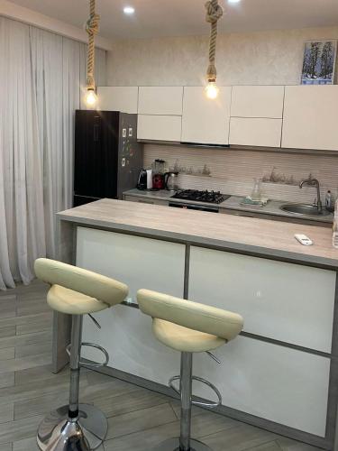 una cocina con 2 taburetes y una barra en sweet home, en Tiflis