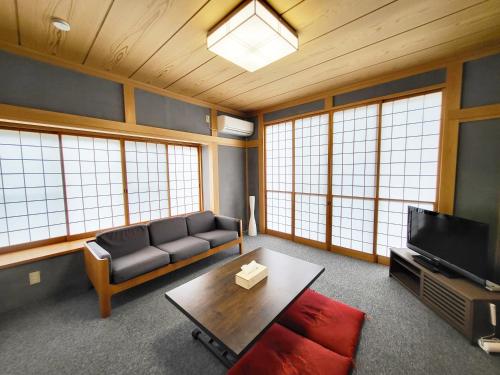 a living room with a couch and a tv at 貸別荘たまゆら in Kawaba