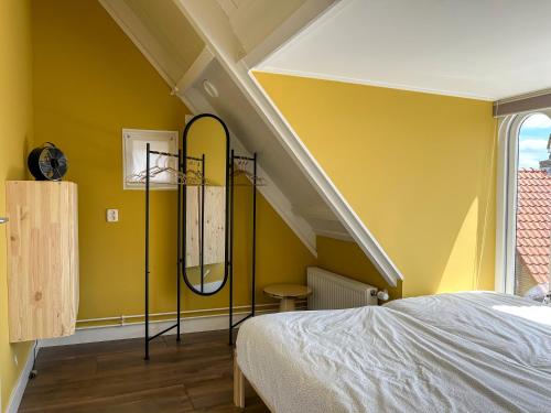 a bedroom with yellow walls and a bed with a mirror at Luxe familie appartement bij de Waegh Dokkum in Dokkum