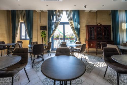 a restaurant with tables and chairs and a large window at Casa Rosanna Malta B&B Adults only 16 plus in Marsaskala