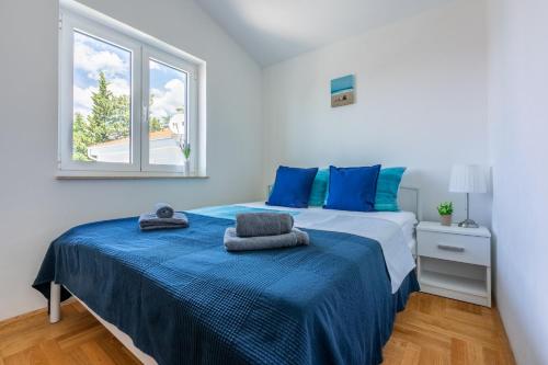 a bedroom with a bed with blue sheets and a window at PODVEZANEC in Dramalj