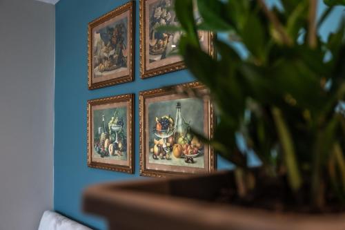 a blue wall with four framed paintings on it at Casa Rosanna Malta B&B Adults only 16 plus in Marsaskala