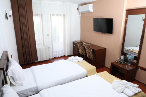 a hotel room with two beds and a mirror at Bruti Hotel in Prizren
