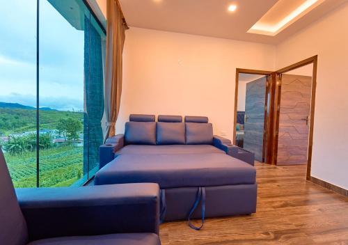 a living room with a couch and a large window at Kodai Outdoor Valley in Kodaikānāl