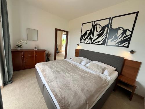 a bedroom with a large bed with three pictures on the wall at Tri Štíty Apartment with Tatra View Terrace in Veľká Lomnica