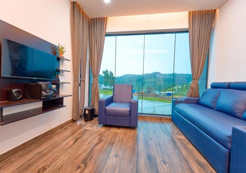 a living room with a blue couch and a large window at Kodai Outdoor Valley in Kodaikānāl