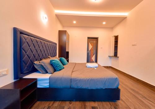 a bedroom with a large bed with blue pillows at Kodai Outdoor Valley in Kodaikānāl
