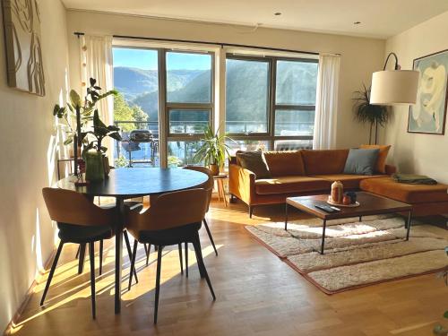 een woonkamer met een tafel en een bank bij Top floor apartment with mountain view, terrace 22sqm, free parking in Bergen