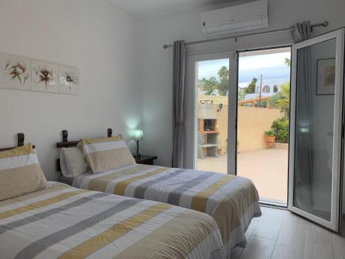 two beds in a room with a sliding glass door at Casa Tia, Mojácar with Private Pool and less than 5 minutes from beach! in Mojácar