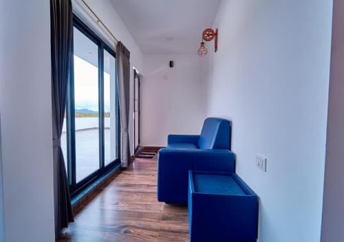 a blue chair in a room with a large window at Kodai Outdoor Valley in Kodaikānāl