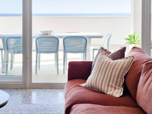 a couch in a living room with a table and chairs at Santorini on Sands, a Sellicks Beach paradise in Sellicks Beach