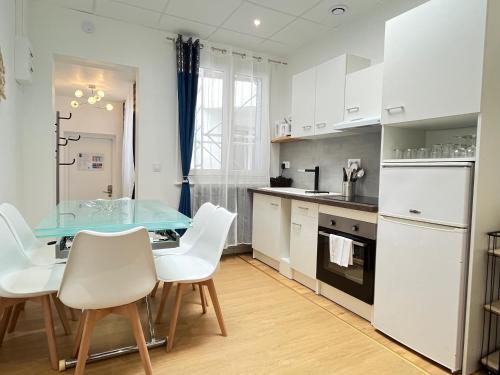 une cuisine avec une table en verre et des chaises blanches dans l'établissement Résidence Harmony, à Vichy