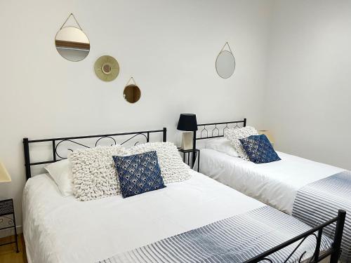 deux lits dans une chambre aux murs blancs dans l'établissement Résidence Harmony, à Vichy