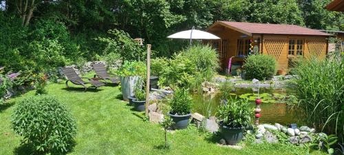 a garden with a pond and chairs and a cabin at Ferienwohnung Blumäcker Oberbayern in Oberhausen