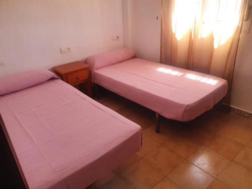 two beds in a room with pink sheets at Casa DOÑANA in Matalascañas