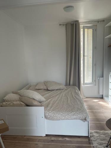 un lit blanc dans une chambre blanche avec une fenêtre dans l'établissement Cosy Studio - near Paris, à Boulogne-Billancourt