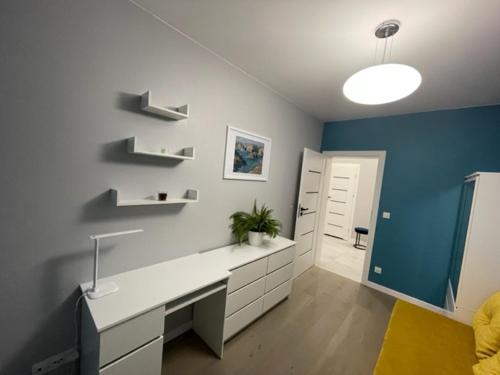 een badkamer met een wit bureau en een blauwe muur bij AK Apartamenty Centrum in Białystok