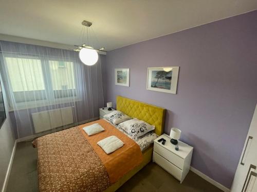 een slaapkamer met een bed met een geel hoofdeinde bij AK Apartamenty Centrum in Białystok