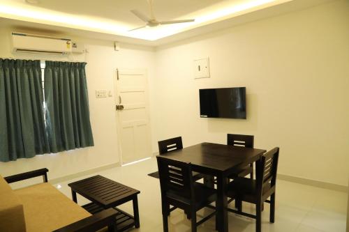 Un comedor con mesa y sillas y un televisor. en F-2 Tulsi By The Peace, en Chennai