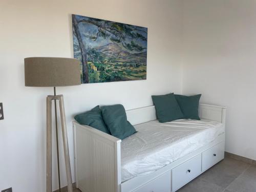 a white bed with green pillows and a painting on the wall at L'Adret in Rians