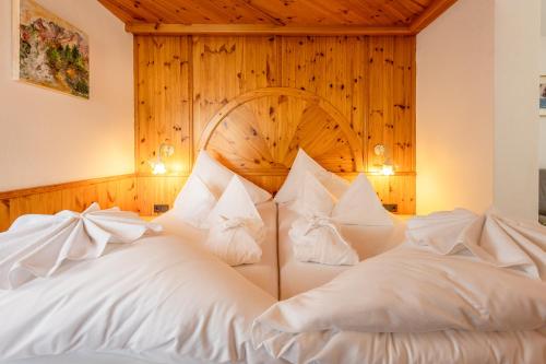 a bedroom with a large bed with white pillows at Hotel Berghof in Neustift im Stubaital